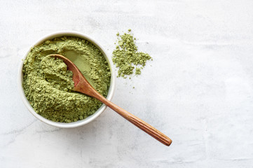 Green matcha tea powder with spoon on white concrete background. Top view. 