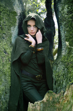 she-elf dressed in cloak with hood color of khaki in a dense the forest