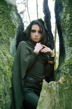 she-elf dressed in cloak with hood color of khaki in a dense the forest