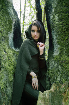 she-elf dressed in cloak with hood color of khaki in a dense the forest