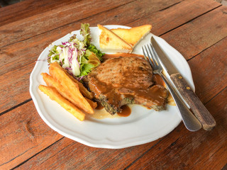 Juicy grilled steak pork chop with salad, french fries and toasts