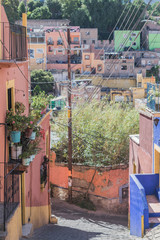 Fototapeta na wymiar Hilly stone paved streets, with colorful houses, potted plants, and other architectural details, in Guanajuato, Mexico