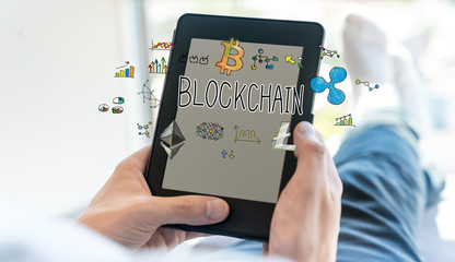 Blockchain text with man using a tablet computer