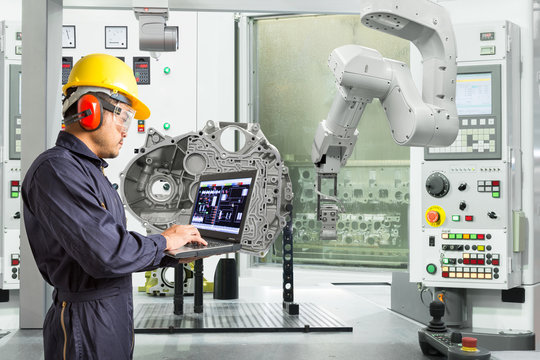 Engineer using laptop computer control automatic robotic hand with CNC machine in automotive industry, Smart factory concept