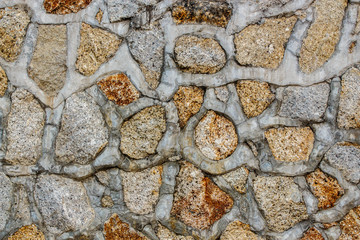 Close up view of  old garden stone wall. Pattern with vertical natural lines and a grey rough surface in background. Wall made of blocks of stones. Abstract composition.