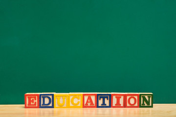 Colorful Education word wood block on wood table with green blackboard,Study concept.copy space for display of design or content.