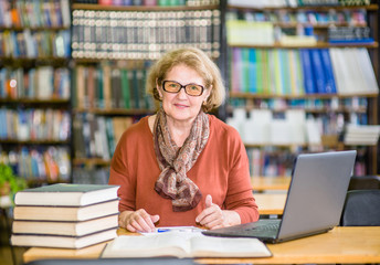 Happy senior woman using laptop in library