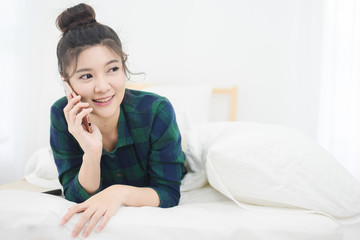 Beautiful Asian Woman lying on her bed and use mobile phone