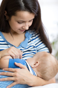 Young mother holding baby. Mom nursing child. Woman breast feeding newborn kid.