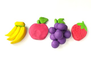 Delicious variety fruits made from plasticine clay on white background, colorful banana apple grapes strawberry dough