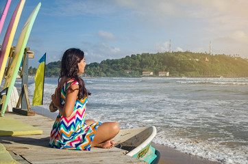 A girl in the colourful dress on the beach is doing yoga, Galle, Sri Lanka