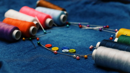 Background jeans fabric, thread, needles with threads, colorful background. Concept sewing...