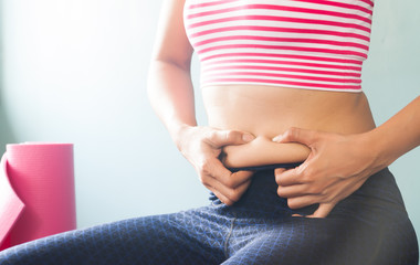 Woman in sport clothing holding excessive belly fat, Healthy and Beauty concept