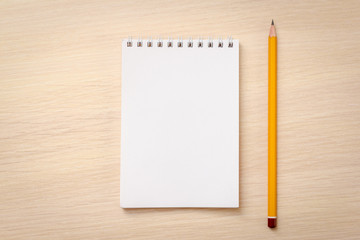 Blank notebook and pencil on wooden background