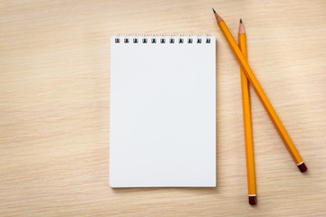 Blank notebook and two pencils on wooden background