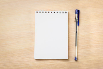 Notebook with pen on wooden background