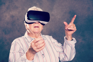 gray hairy elderly woman using virtual reality glasses