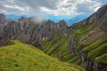 Green grassy hill  mountain ridge under cloudy sky in Alps