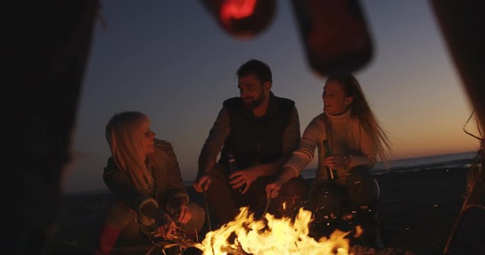 Friends having fun by bonefire at beach