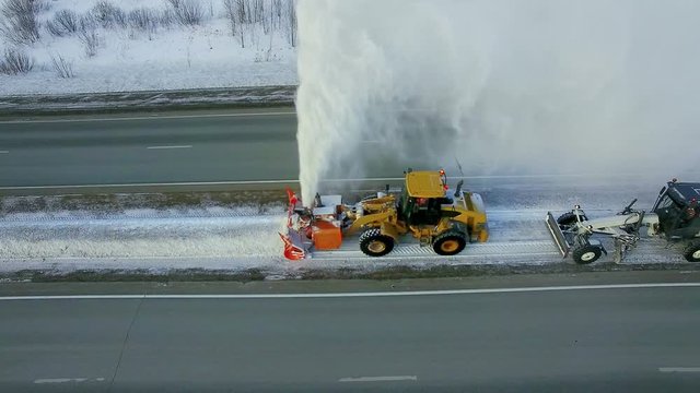 Grader clean remove snow, snowplow, snow blower, blast snowfall, winter, road, special vehicle on the highway, cool frozen fountain of snow aerial view