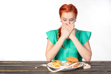 young woman covers her mouth with both hands so as not to eat fast food