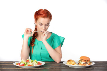 young woman making choice between salad and hamburger