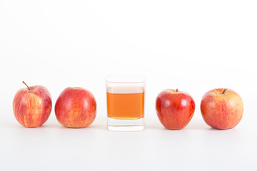 Cup of apple cider vinegar and four apples on white background.
