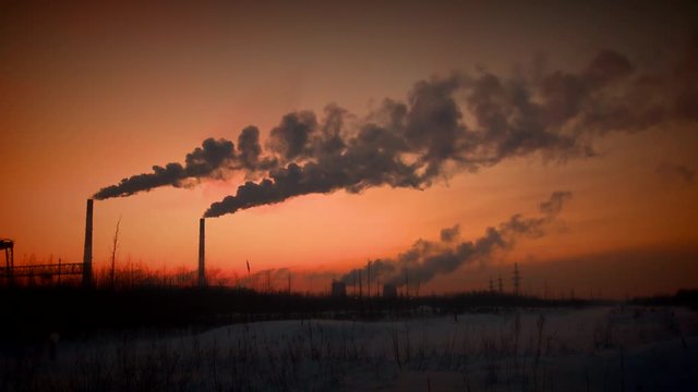 Factory chimneys smoke in the crimson sunset. Air pollution by carcinogens from industrial waste. Violation of environmental contamination of the atmosphere the remnants of combustion.   