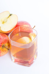Apple cider vinegar in a glass cup and fresh apples on white background.