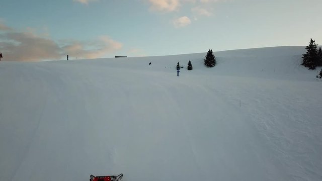 Drone aerial view of a snow groomer as it climbs the mountain for preparation of the ski slopes