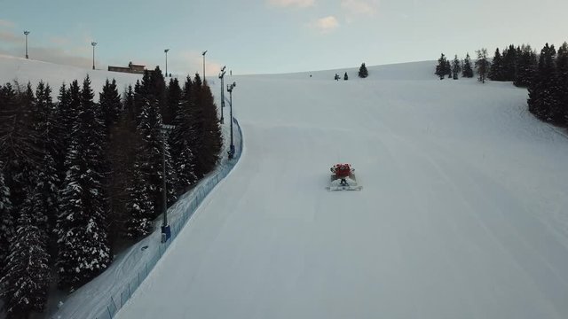 Drone aerial view of a snow groomer as it climbs the mountain for preparation of the ski slopes