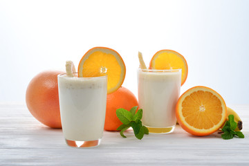 Smoothies with bananas and oranges, a sprig of mint on a white background. Space for text or design.