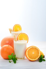 Smoothies with bananas and oranges, a sprig of mint on a white background. Space for text or design.