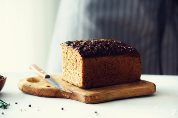 Woman hands slicing freshly backed bread. Handmade brown loaf of bread, bakery concept, homemade food, healthy eating. Copy space