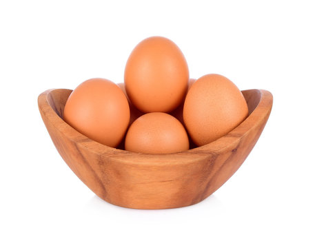 six fresh eggs in a curved wooden bowl isolated on white background.