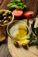 olive oil with twig beside on wooden table
