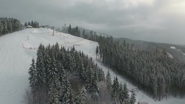 Skiers and snowboarders go down the slope in a ski resort. Winter forest. Aerial view
