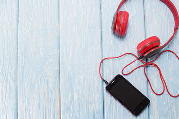 mobile phone with headphones on light blue background.