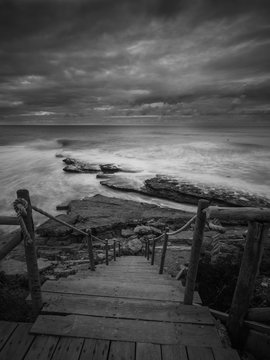 Beautiful rocky beach in the Portuguese coastline in a stormy day. Seascape. Long exposure.