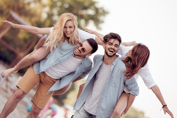 Obraz premium Young happy people carrying women on a sandy beach.