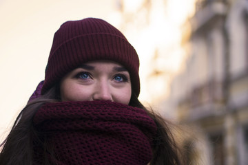 Pretty Brunette Girl Wearing Purple Winter Coat, Hat and Scarf, Walking by European Street at Winter, Wrapped up in a Scarf.