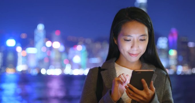 Woman send message on cellphone at Hong Kong at night