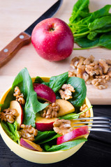 Spinach salad with nuts and apples served on table