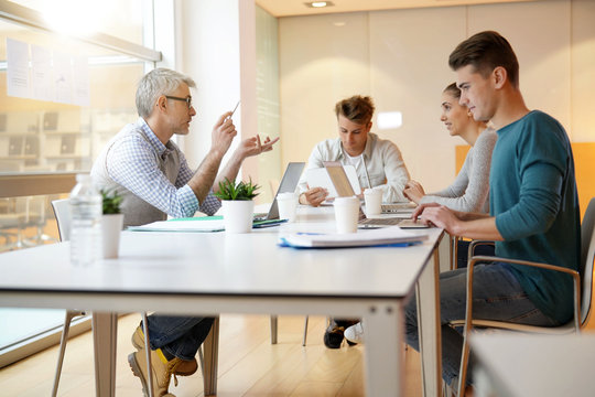 Teacher meeting around table with students