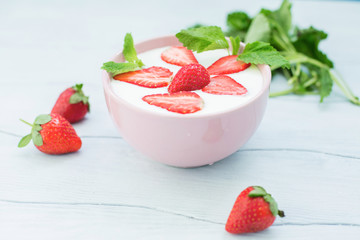 Eating healthy breakfast .Yogurt with strawberries  in a bowl on the table