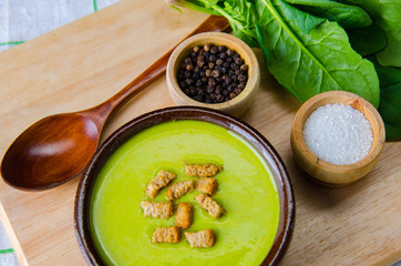 Spinach soup served on wooden board 