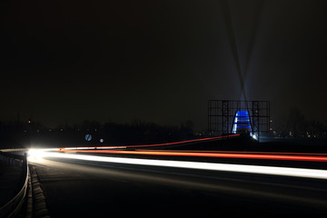 Fototapeta na wymiar Światła samochodów w nocy i smugi świateł oświetlające wiadukt.