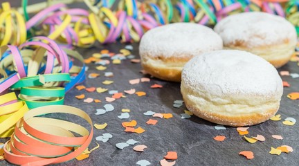 Krapfen und Faschingsdekoration auf einer Schieferplatte 