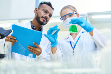 Low angle portrait of international team of scientists working together in medical laboratory doing research on  chemicals and bacteria