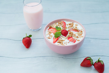 Eating healthy breakfast .Yogurt with strawberries and granola in a bowl on the table
